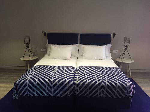 a large bed with blue and white sheets and pillows at Hotel Casa Hintze Ribeiro in Ponta Delgada