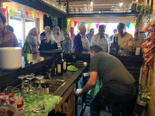 a group of people standing in a kitchen with a bartender at Chalet 531a op Recreatiepark De Wielen in Sint Maarten