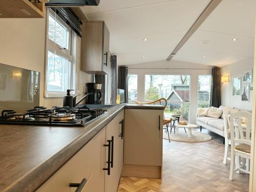 a kitchen with a stove top oven next to a living room at Chalet 531a op Recreatiepark De Wielen in Sint Maarten