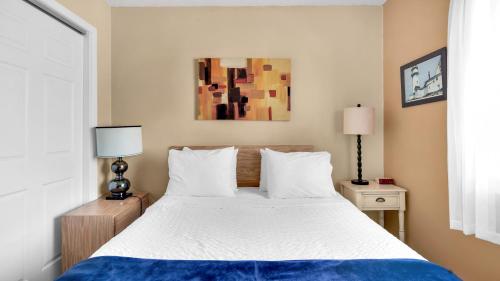 a bedroom with a bed with white sheets and two lamps at Montauk Oceanside Suites in Montauk