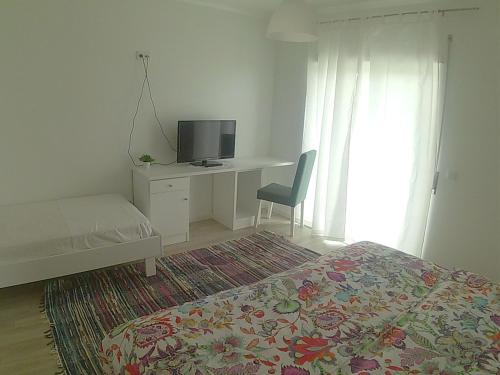 a bedroom with a bed and a desk with a television at Hotel Baleal Spot in Baleal