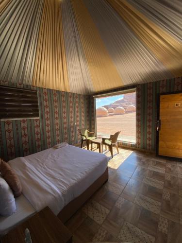 a bedroom with a bed and a table and a window at مخيم الانيق in Wadi Rum