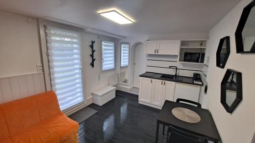 eine Küche und ein Wohnzimmer mit weißen Schränken und einem Tisch in der Unterkunft Studio Volta Garden in Tours