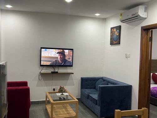 a living room with a couch and a tv on a wall at American mall in Accra