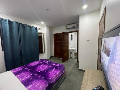 a bedroom with a purple bed and a bathroom at American mall in Accra