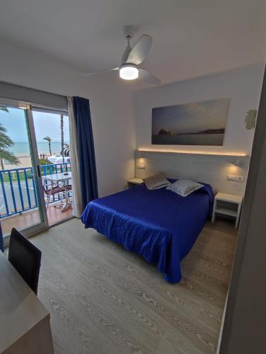 a bedroom with a blue bed and a balcony at Hotel Rio Mar in Peniscola