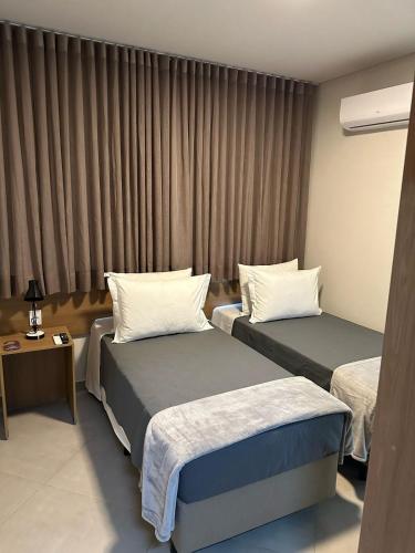 a hotel room with two beds and a window at Hotel Cabana in Caetanópolis