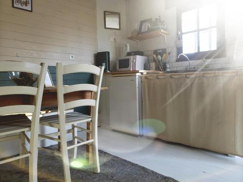cocina con mesa, 2 sillas y barra en La petite forêt en Mons-Boubert