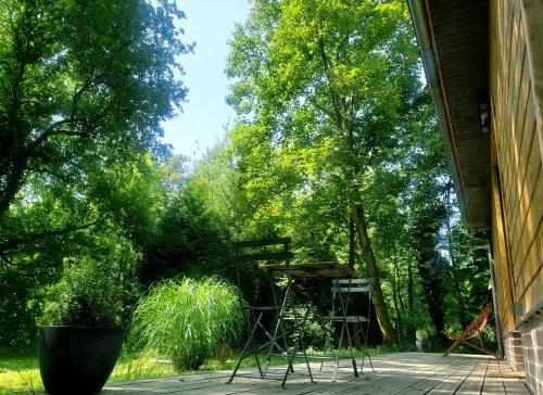 un porche con sillas, mesa y árboles en La petite forêt en Mons-Boubert