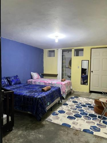 1 dormitorio con 2 camas y pared azul en Mi fe apartamento en Esquipulas