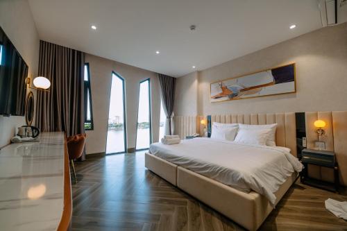 a bedroom with a large bed and large windows at La Beaute Hotel - Quy Nhơn in Quy Nhon