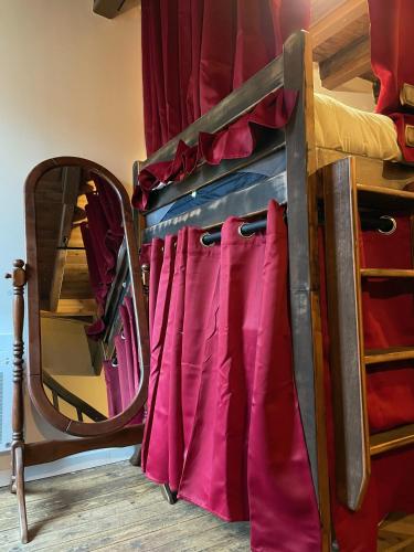 a bunk bed with red and purple sheets and a mirror at Impasse des Mystères - La maison des Sorciers Léhon/Dinan in Dinan