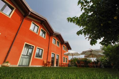 an orange building with tables and umbrellas in a yard at Albergo della Ceramica in Villanova Mondovì