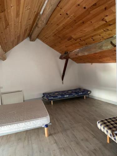 a room with two beds and a wooden ceiling at Maison de montagne 8 couchages in Aston