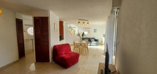Il comprend un salon avec une chaise rouge et une cuisine. dans l'établissement LE NADIR GRAND T2 51m2, 4-5p, Parking, à Fréjus