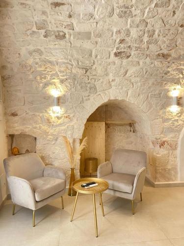 2 sillas y una mesa en una habitación con una pared de piedra en Eureka luxury room, en Ostuni