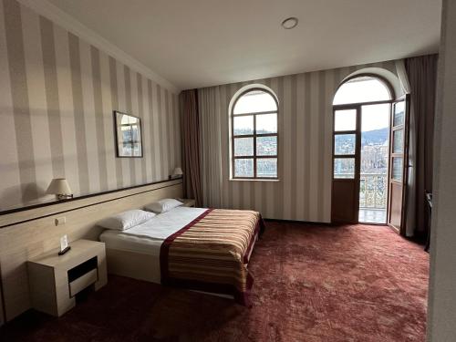 ein Hotelzimmer mit einem Bett und zwei Fenstern in der Unterkunft Hotel Europe plaza in Tbilisi City