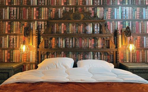 a bed in front of a wall of books at Impasse des Mystères - La maison des Sorciers Léhon/Dinan in Dinan