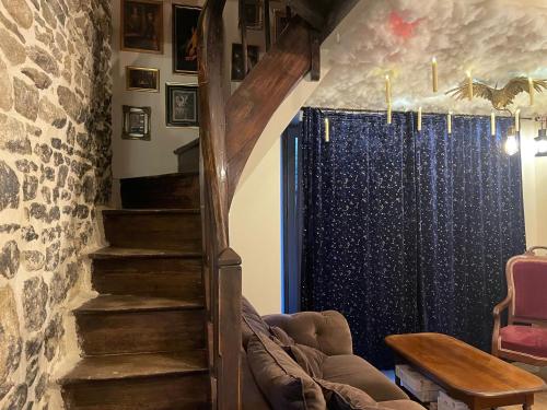 a living room with a staircase and a stone wall at Impasse des Mystères - La maison des Sorciers Léhon/Dinan in Dinan