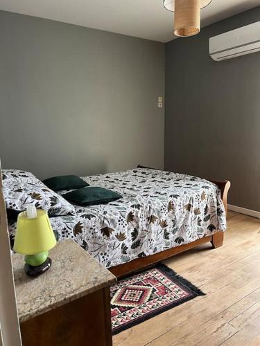 a bedroom with a bed and a table with a lamp at Le cocon d'Ali in Langon