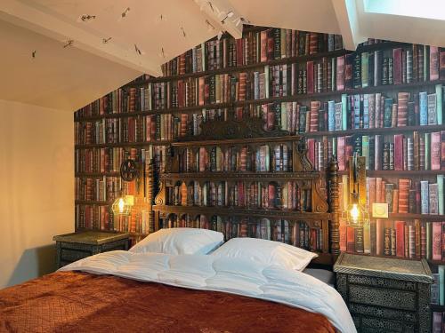 a bedroom with a large wall of books at Impasse des Mystères - La maison des Sorciers Léhon/Dinan in Dinan