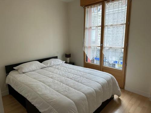 une chambre avec un grand lit blanc avec une fenêtre dans l'établissement Appartement T4 au cœur de Dinard, à Dinard