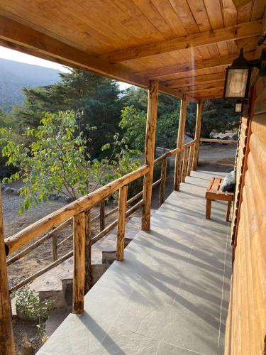 a wooden porch with a view of the ocean at Cabañas Parque Almendro in San José de Maipo