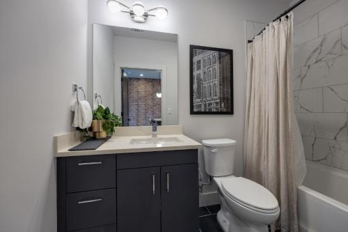 a bathroom with a toilet and a sink and a mirror at Vesta - Odyssey - Heart of Midtown in Nashville