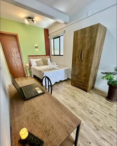 a room with a bed and a desk with a laptop at Espaço da Zilda in São José