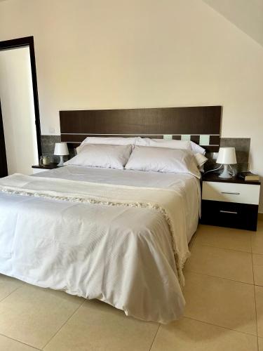 a large white bed with two night stands and two lamps at Caleta alto in Caleta De Fuste