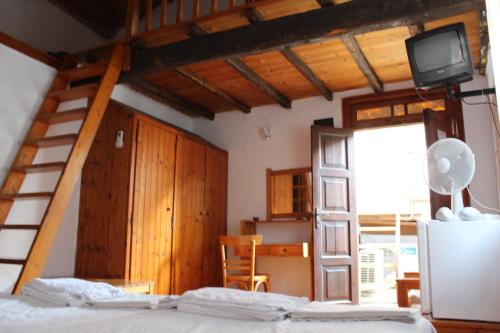 a bedroom with a bed and a staircase and a television at Sotos pension in Skopelos Town