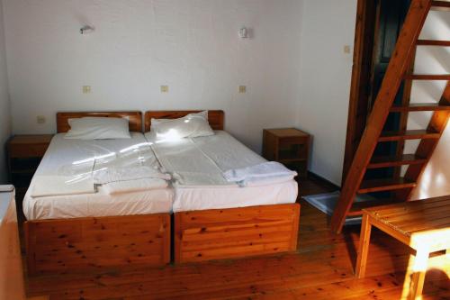 a bedroom with a bed with a wooden frame and a ladder at Sotos pension in Skopelos Town