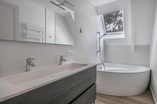 une salle de bain blanche avec une baignoire et un lavabo dans l'établissement Pause détente et plage à la Baule-Escoublac, à La Baule