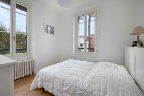 une chambre blanche avec un lit et deux fenêtres dans l'établissement Pause détente et plage à la Baule-Escoublac, à La Baule