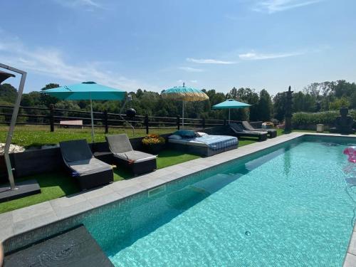 a swimming pool with two chairs and umbrellas at Familie & Vriendenwoning met fantastisch uitzicht in Ellezelles