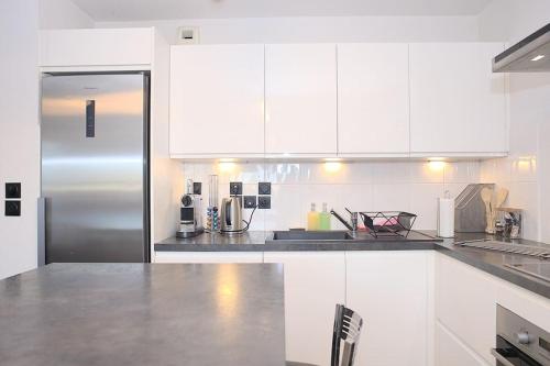 une cuisine avec des armoires blanches et un réfrigérateur en acier inoxydable dans l'établissement Cosy Duplex - Ma Cabotte, à Toulouse