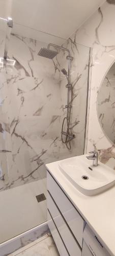 a white bathroom with a sink and a mirror at Appartement de standing in Créteil