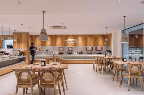a restaurant with wooden tables and chairs and a kitchen at SKYLA Studios & Suites - Kondapur in Hyderabad