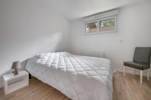 a white bedroom with a bed and a chair at Appartement dans résidence calme à 100m de la plage in Saint-Brévin-lʼOcéan