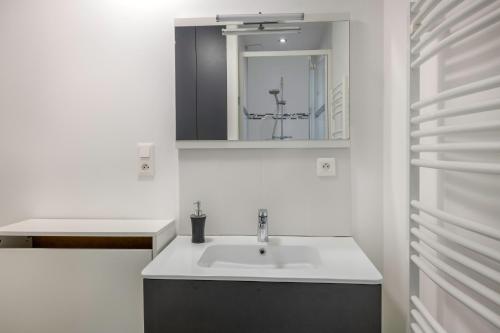 a white bathroom with a sink and a mirror at Appartement dans résidence calme à 100m de la plage in Saint-Brévin-lʼOcéan