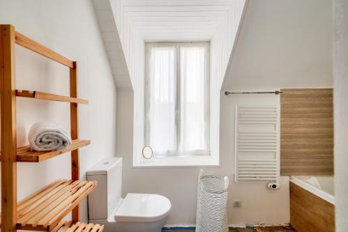 a bathroom with a toilet and a sink and a window at À 700m de la plage, charmante maison pour 6 in Kersuluan
