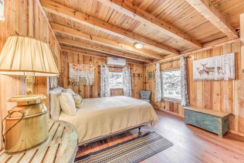 a bedroom in a log cabin with a bed and a lamp at Ruidoso Cabin with Hot Tub - 2 Mi to Grindstone Lake in Ruidoso