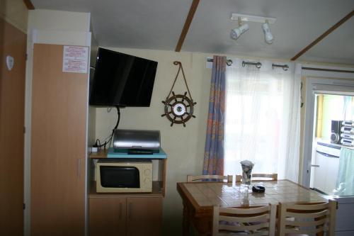 a kitchen with a table with a microwave and a television at Chez Eponine in Dannes