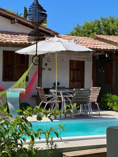 ein Haus mit einem Pool mit einem Tisch und einem Sonnenschirm in der Unterkunft Vila Uryah in Caraíva