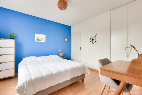 - une chambre avec un mur bleu, un lit et une table dans l'établissement Vacances paisibles à Arès, à Arès
