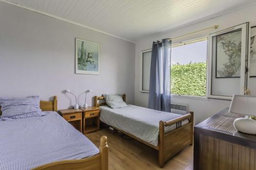une chambre avec deux lits et une fenêtre dans l'établissement Maison avec piscine 4 chambres, 8 couchages Biscarrosse Bourg proche centre ville., à Biscarrosse
