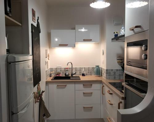 a small kitchen with white cabinets and a sink at Appartement face mer in Quend