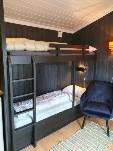 a bedroom with two bunk beds and a chair at Bjørgebu campung as in Mysusæter