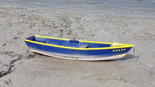 a blue and yellow boat sitting on the beach at Baie de somme in Quend