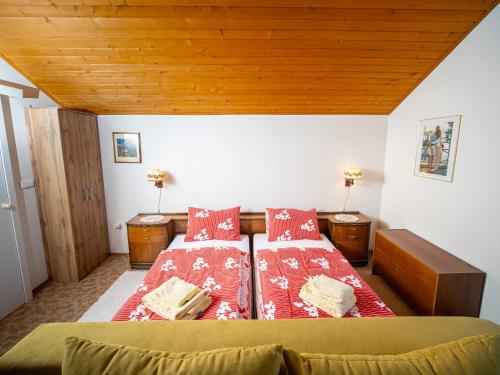 a bedroom with a bed with red sheets and wooden ceilings at Ubytovanie Clematis in Martinske Hole